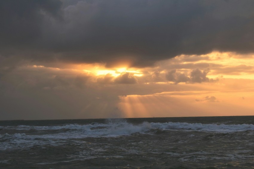 the sun is shining through the clouds over the ocean