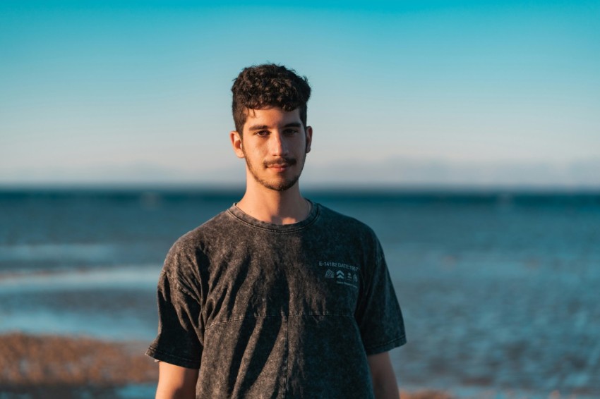 man in black crew neck t shirt standing near body of water during daytime