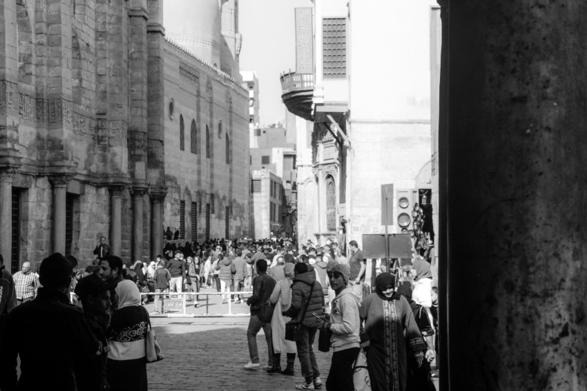 a crowd of people walking down a street next to tall buildings