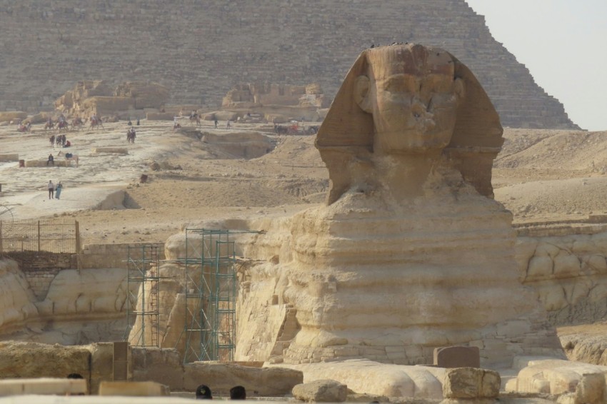 a large rock sculpture in a desert with great sphinx of giza in the background