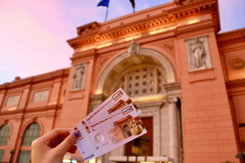 a person holding up two bills in front of a building