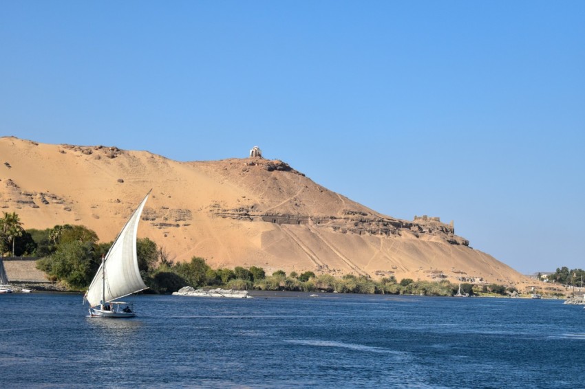 a sailboat in a body of water with a mountain in the background