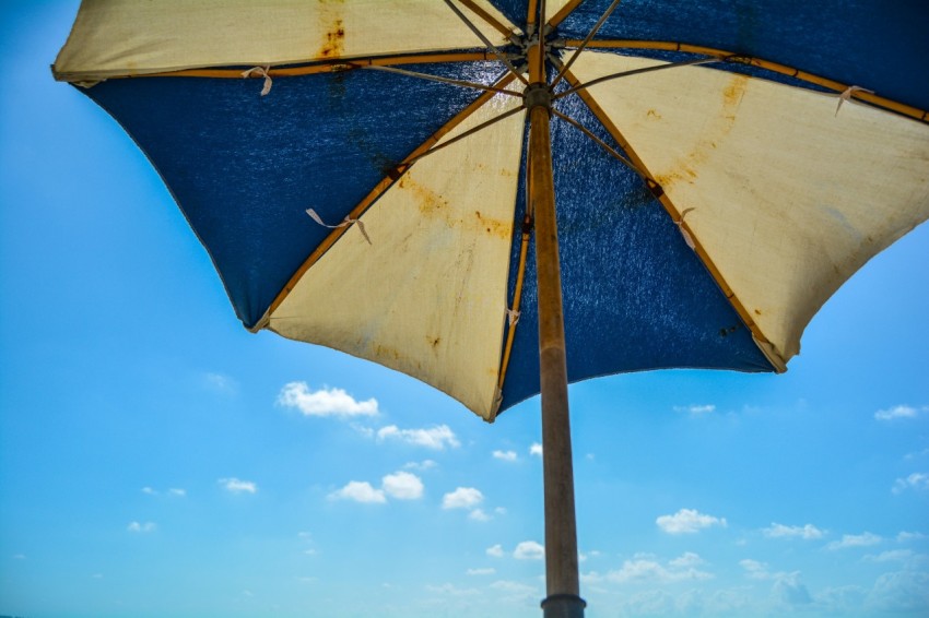 a blue and yellow umbrella sitting on top of a beach