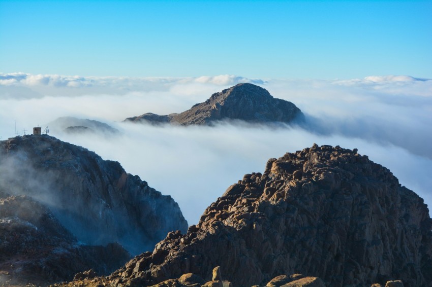 a mountain with a tower in the middle surrounded by clouds