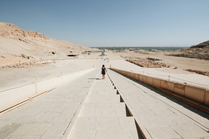 person walking on gray concrete pathway near sea during daytime