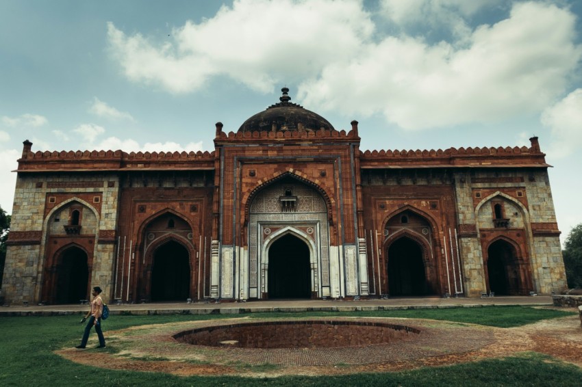 a large building with a person walking in front of it with purana qila in the background