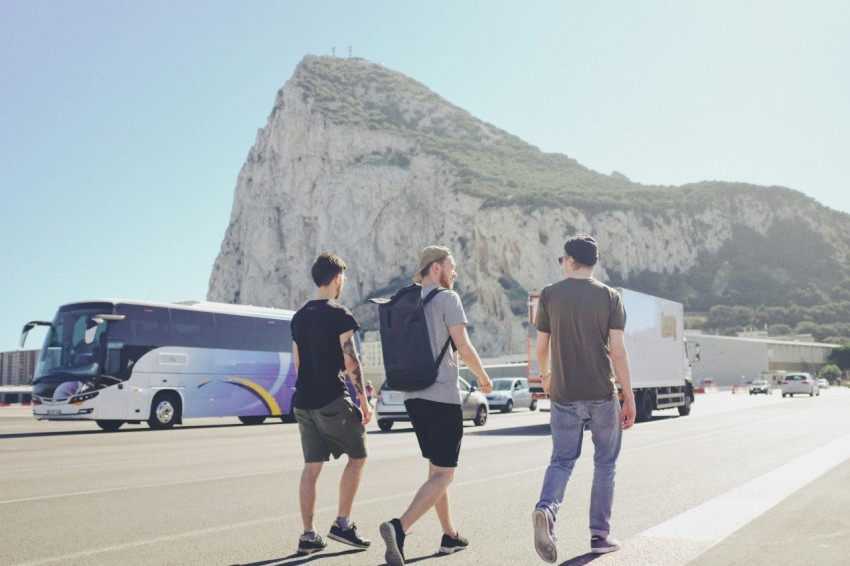 three men walking on street near vehicles during daytime