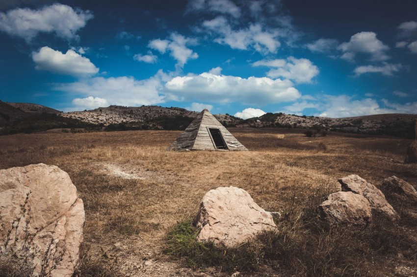 pyramid gray tent on brown field under white clouds mvQXm