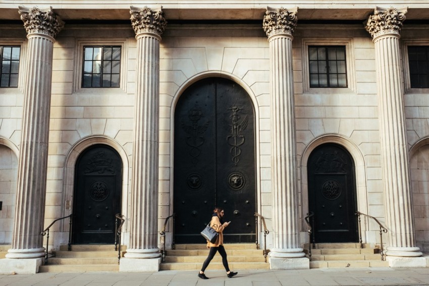 woman walking in front of white building with ionic pillars jeF