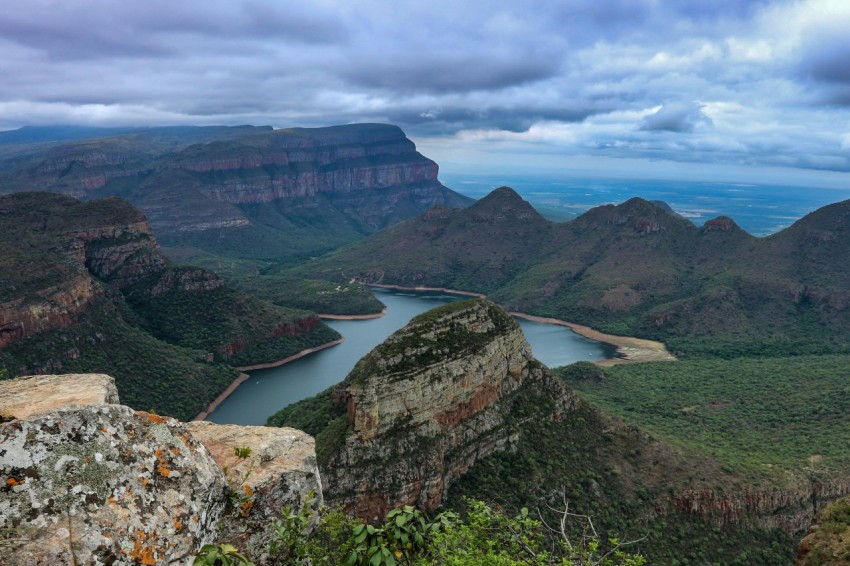 body of water and green mountain under blue sky