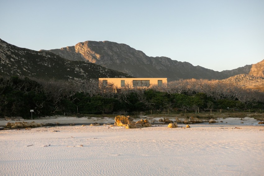 a house in the middle of a desert with mountains in the background