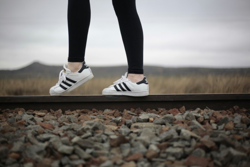 person wearing white and black adidas superstar