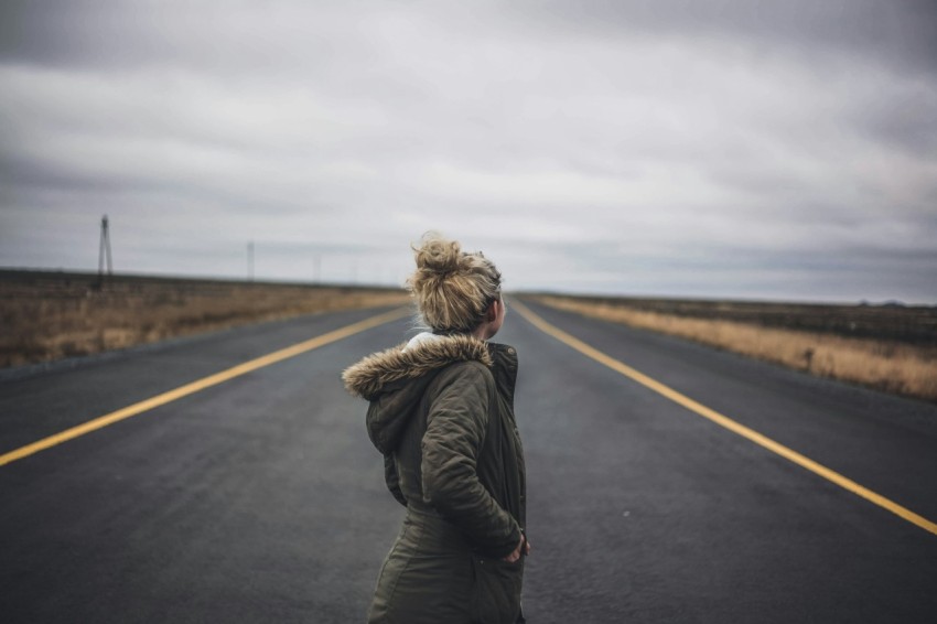 woman in black jacket standing on road during daytime