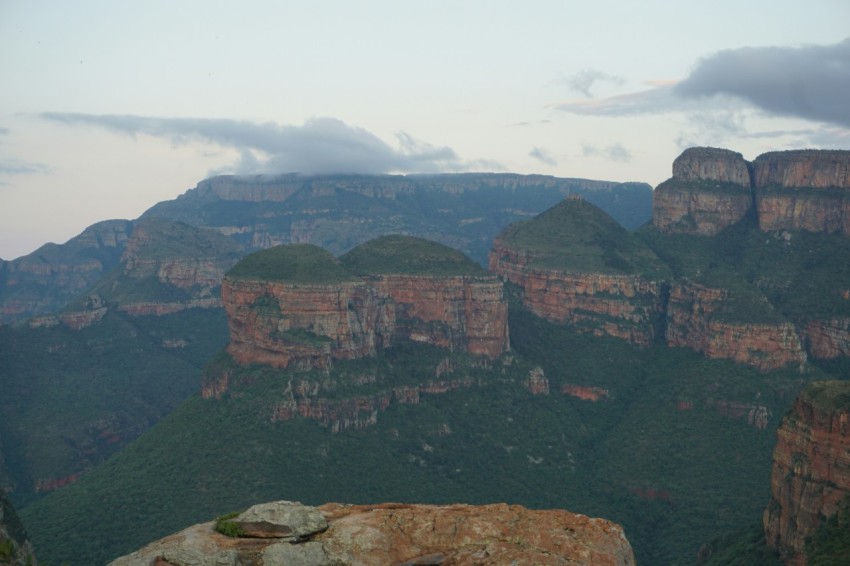 a person sitting on a rock looking at the mountains