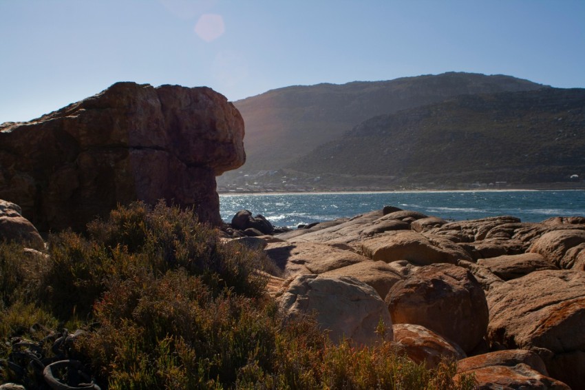 a rocky beach with a body of water in the background