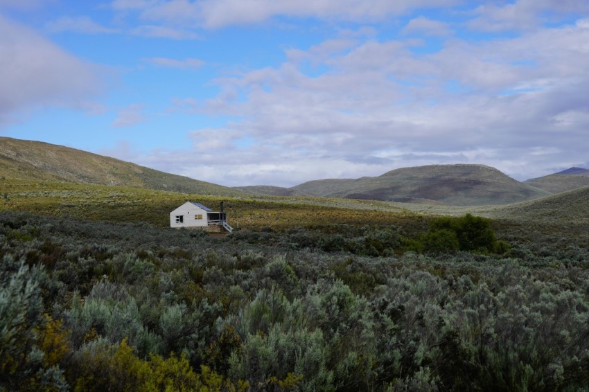 a house in the middle of a field with mountains in the background