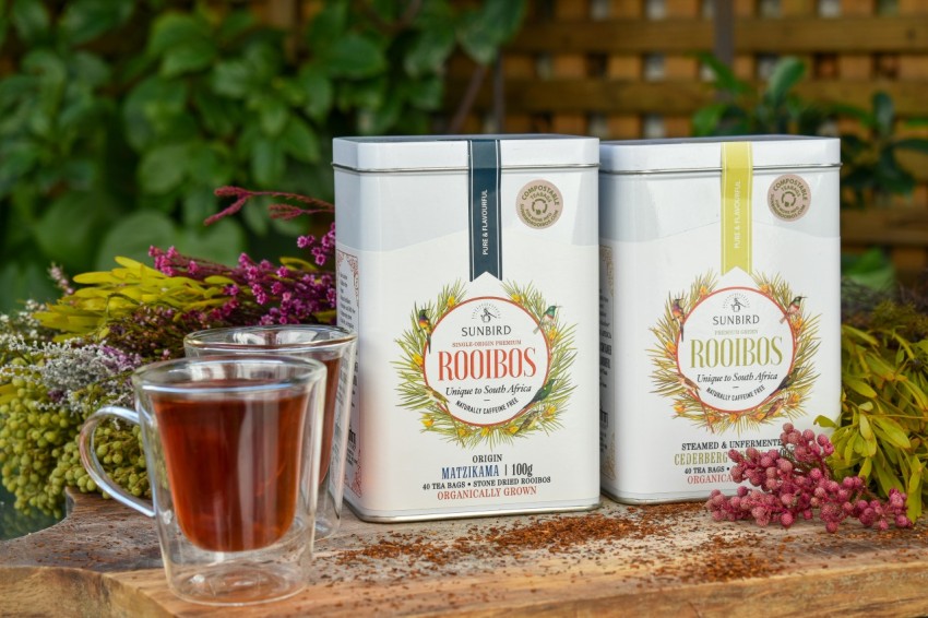 two cans of rooibos tea next to a cup of tea