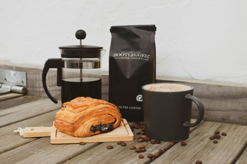 a table topped with a cup of coffee next to a loaf of bread