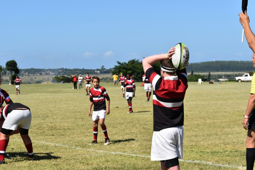 man in red and black jersey shirt holding white and black football