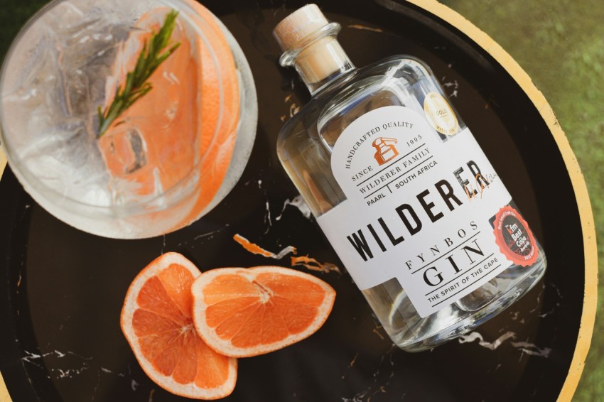 a bottle of wildder gin next to sliced oranges