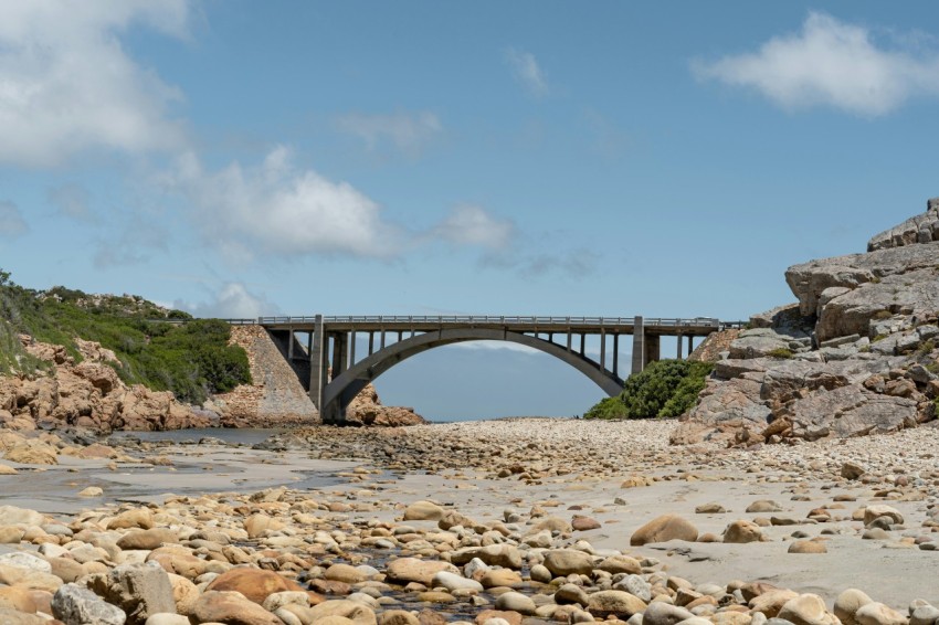 gray concrete bridge over river under blue sky during daytime VZQGZ