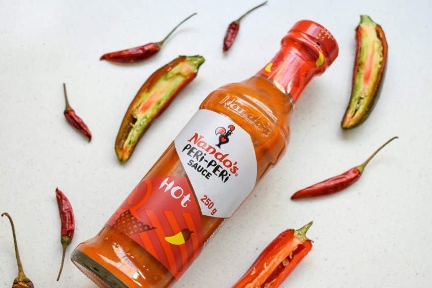 a bottle of hot sauce surrounded by hot peppers 1u