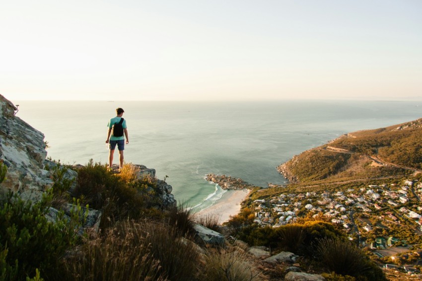 person standing on the edge of cliff overlooking body of water