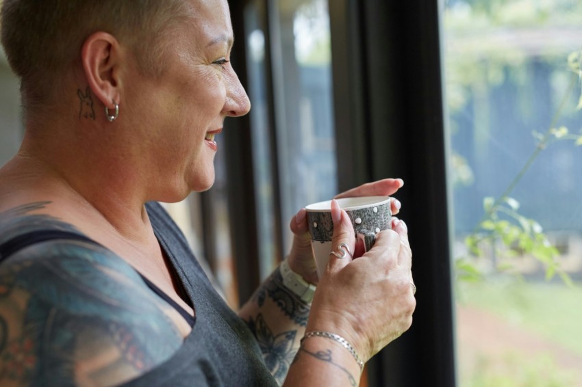 a person holding a cup looking out a window