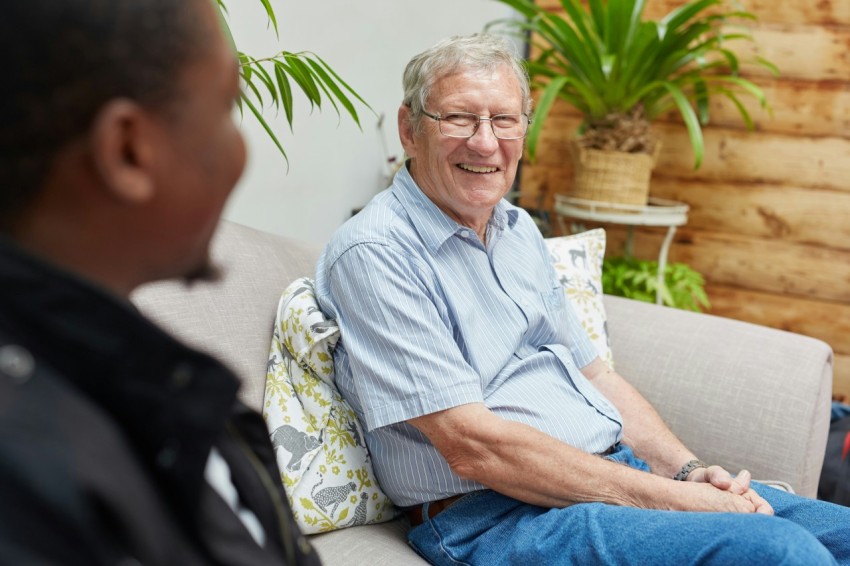 a man sitting on a couch talking to another man