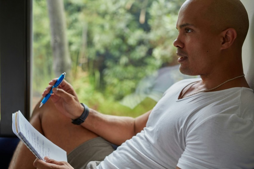 a man sitting on a couch writing on a piece of paper