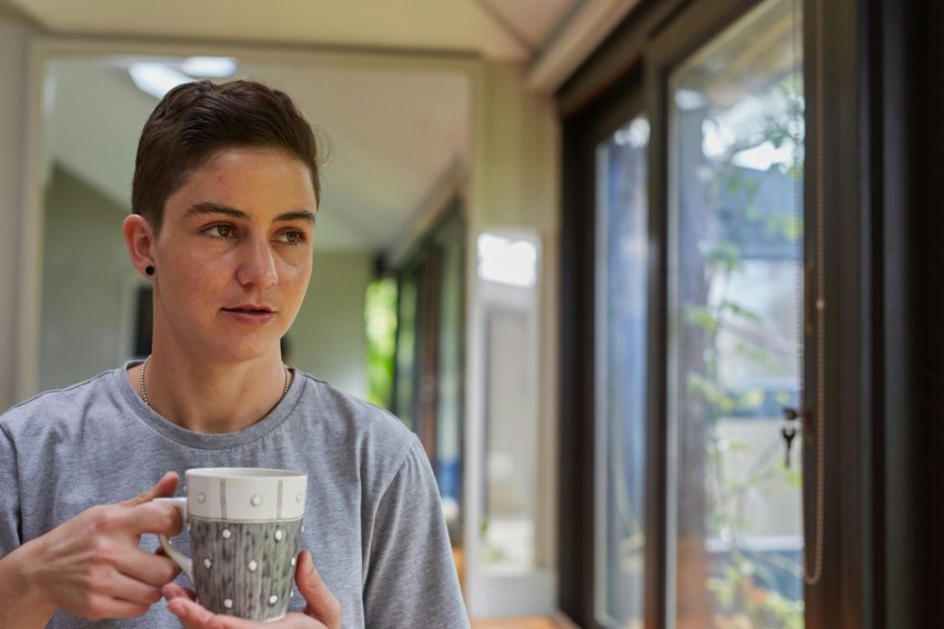 a person holding a cup looking out a window