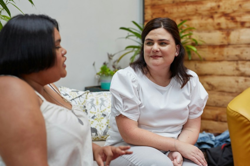 a woman sitting on a couch talking to another woman UuNge_jzG