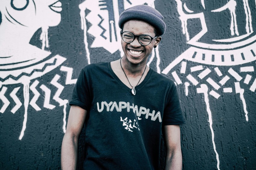 man in blue crew neck t shirt standing beside wall with graffiti