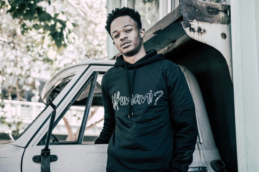 man in blue adidas hoodie standing beside white car during daytime