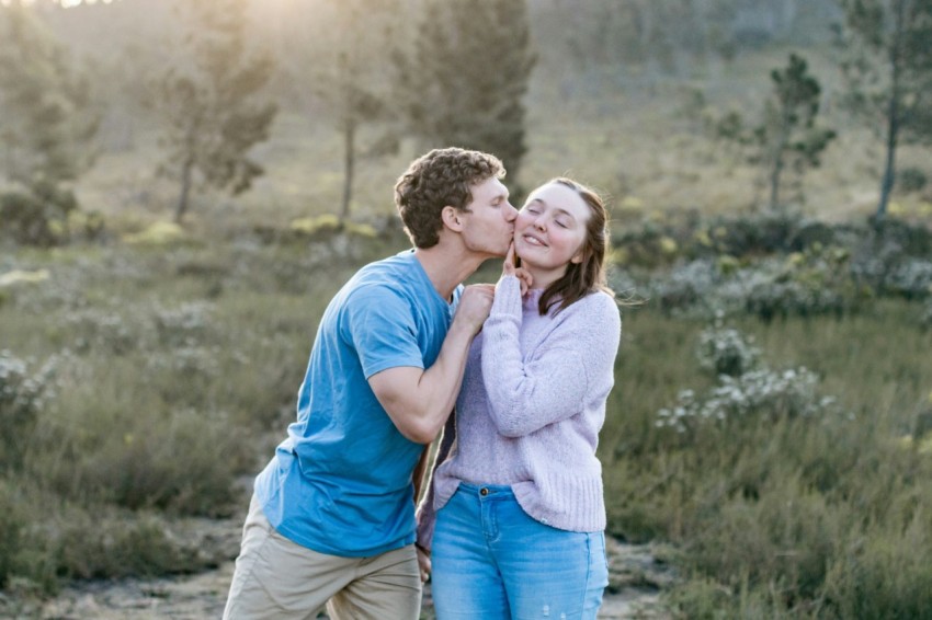 man in blue crew neck t shirt kissing woman in white long sleeve shirt during daytime