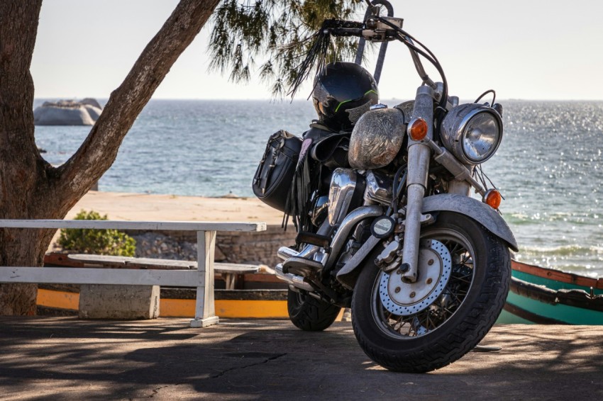 a motorcycle parked next to a tree near the ocean YSEL2iEst