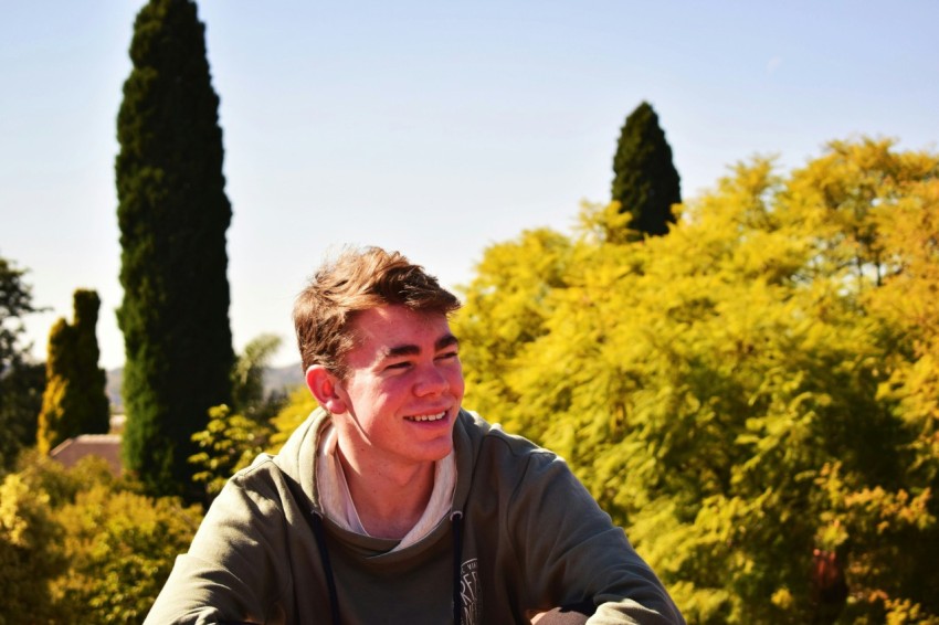 a man sitting in front of a bunch of trees