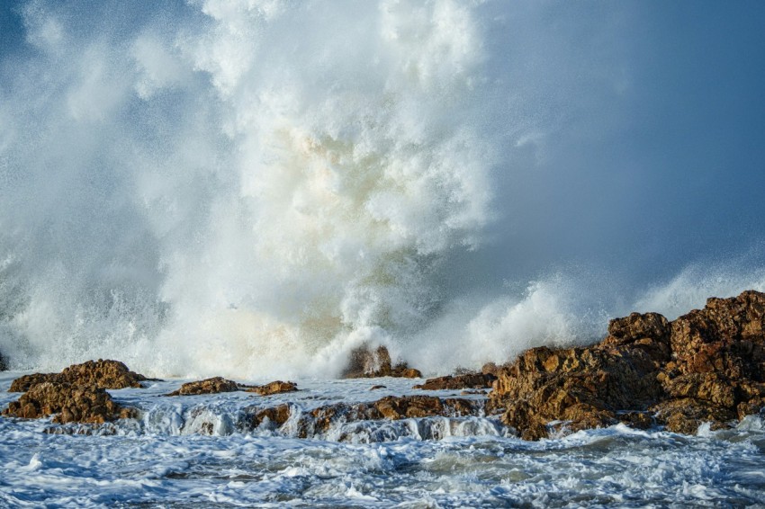 a large wave crashing over rocks in the ocean