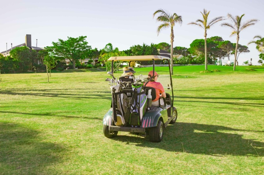 two people on a golf cart in the grass