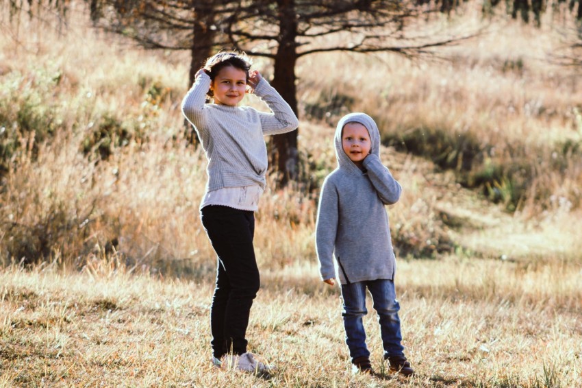 woman in white sweater and black pants standing on brown grass field during daytime