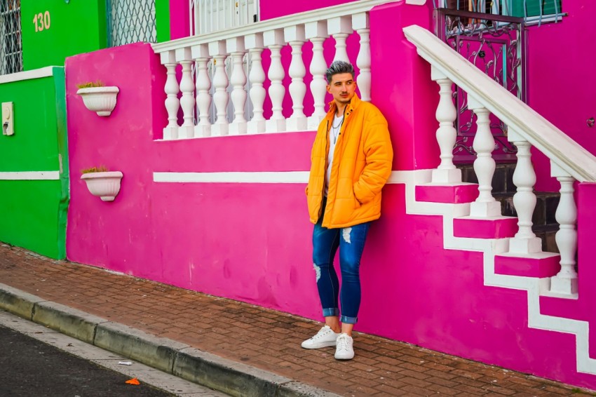 woman in yellow jacket and blue denim jeans standing on brown wooden pathway