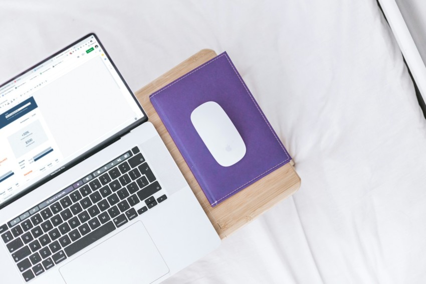 a laptop computer sitting on top of a white bed