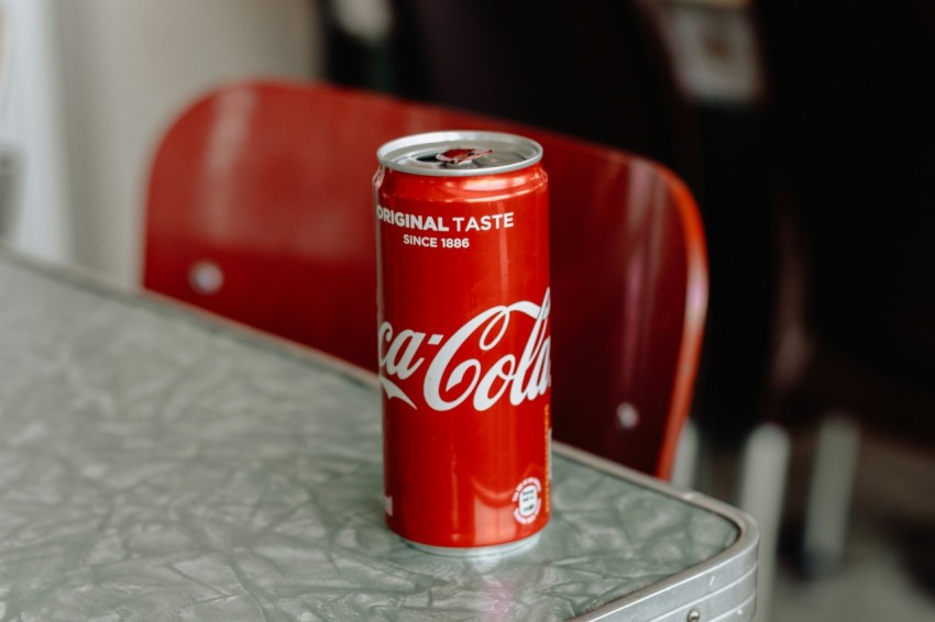 coca cola original taste soda can on edge of gray table