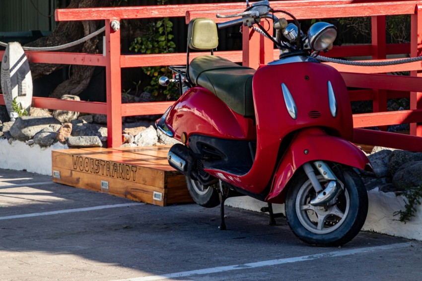 a red scooter parked next to a red fence