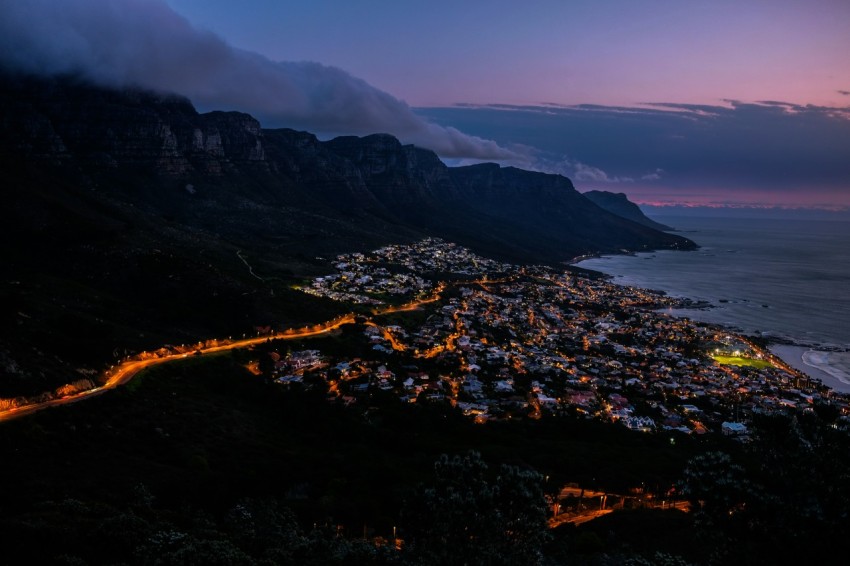 high angle photography of city near smoky mountain and body of water during sunset