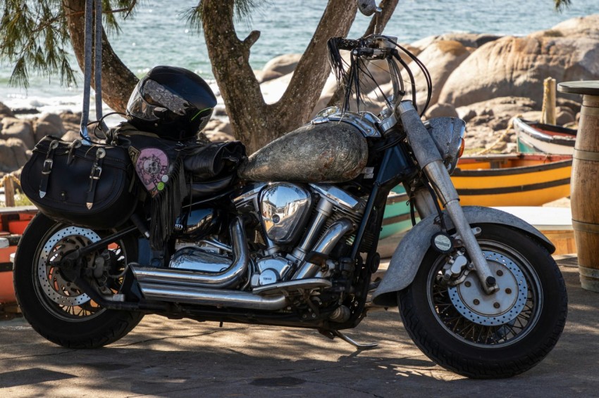 a motorcycle parked next to a tree near the ocean