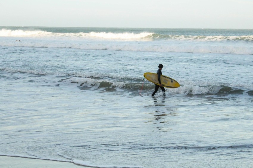 a man walking into the ocean with a surfboard _HWu1Mto