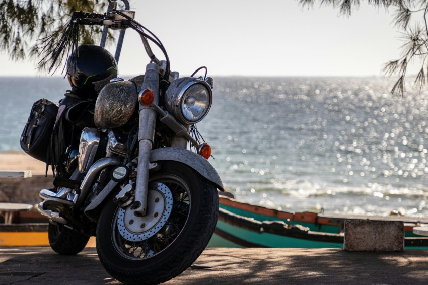 a motorcycle parked on the side of a road next to the ocean O3c2cH7yM