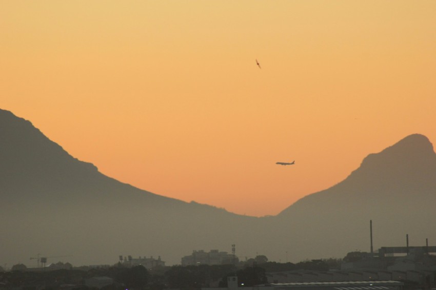 a plane flying over a city with mountains in the background