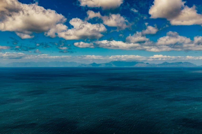 a large body of water under a cloudy blue sky FRpDB